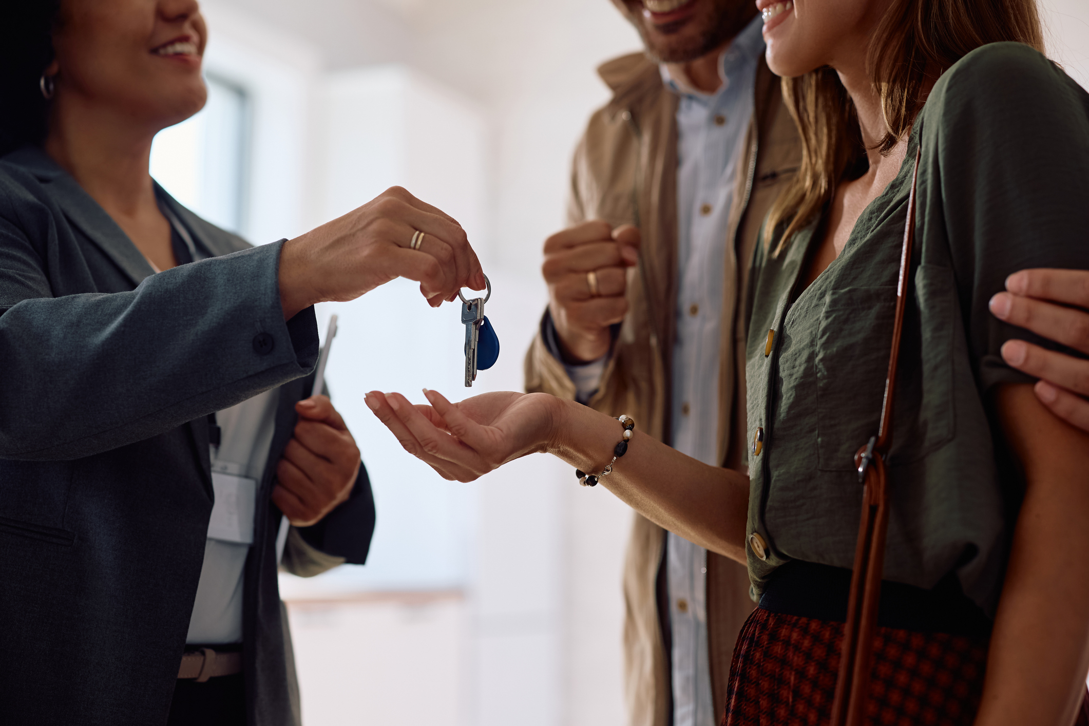 Close up of couple receiving keys of their new home from real estate agent.